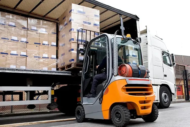 Forklift lifting boxes onto truck