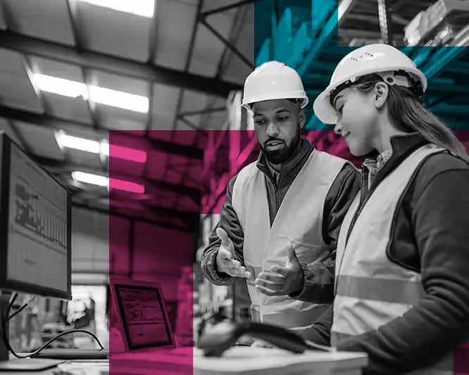 Man and woman in safety gear in warehouse with computer