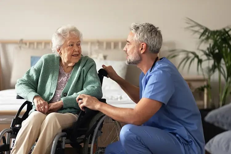 Male nurse speaking to woman in a wheelchair