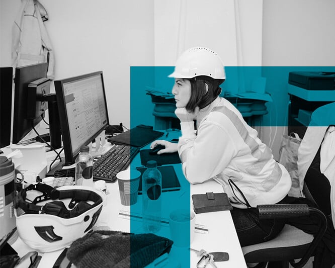 Woman in high vis looking at computer at work desk in office