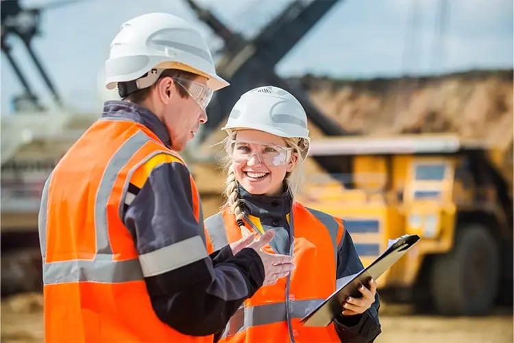 Two workers on construction site in uniform smiling